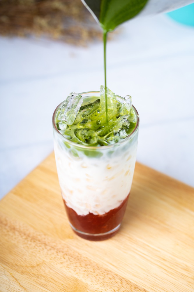 Matcha poured over iced milk and strawberry purée